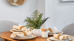 Una mesa de comedor preparada con platos, tazones y una planta en maceta.
