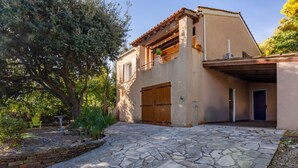 Una casa con un camino empedrado de piedra, una puerta de madera y un balcón con plantas.