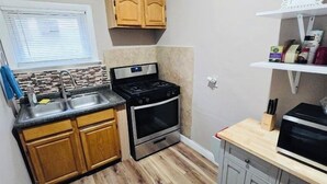 Une cuisine de taille réduite, avec des meubles de rangement en bois, une cuisinière et un évier.