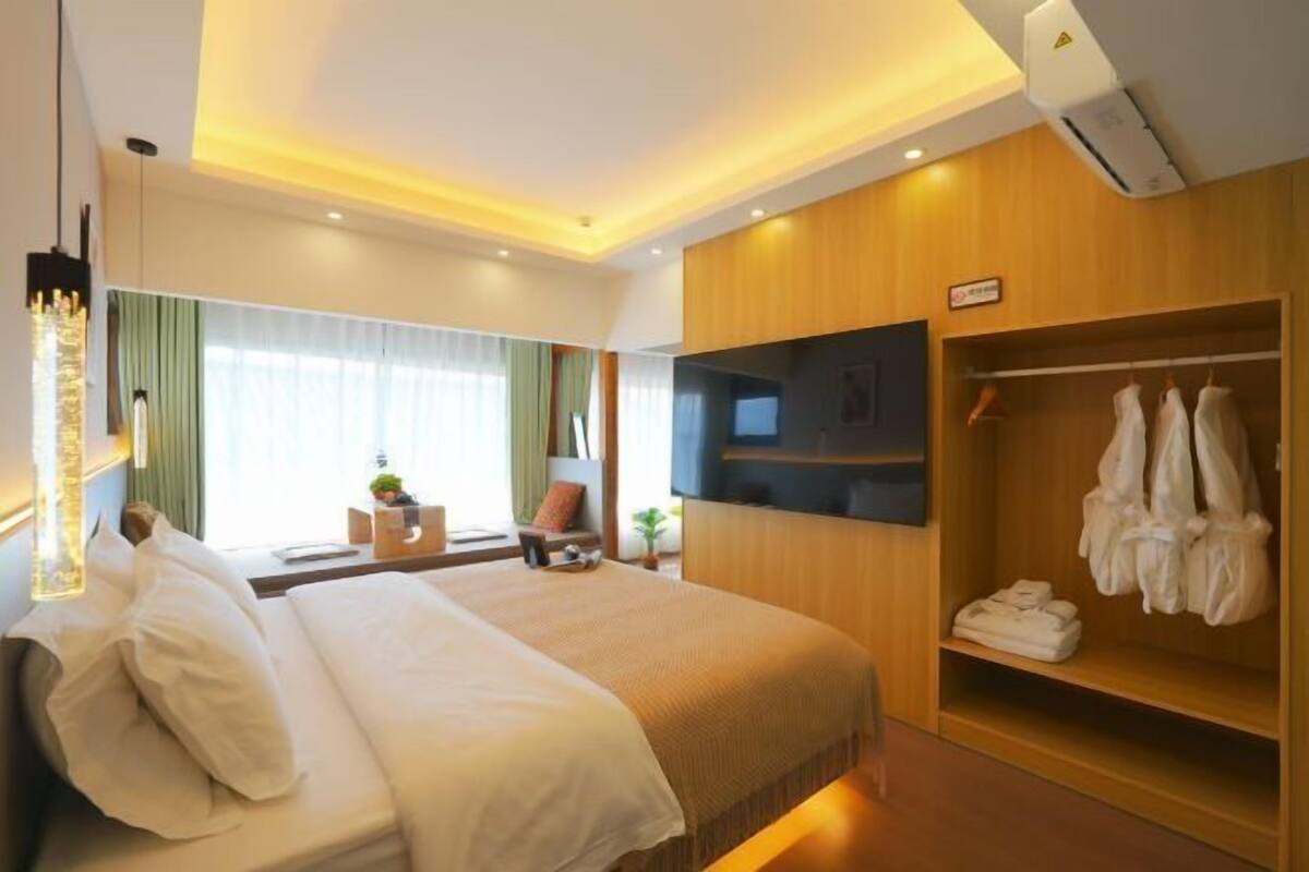 Une chambre d’hôtel avec un grand lit, une télévision, une armoire et une table de chevet.