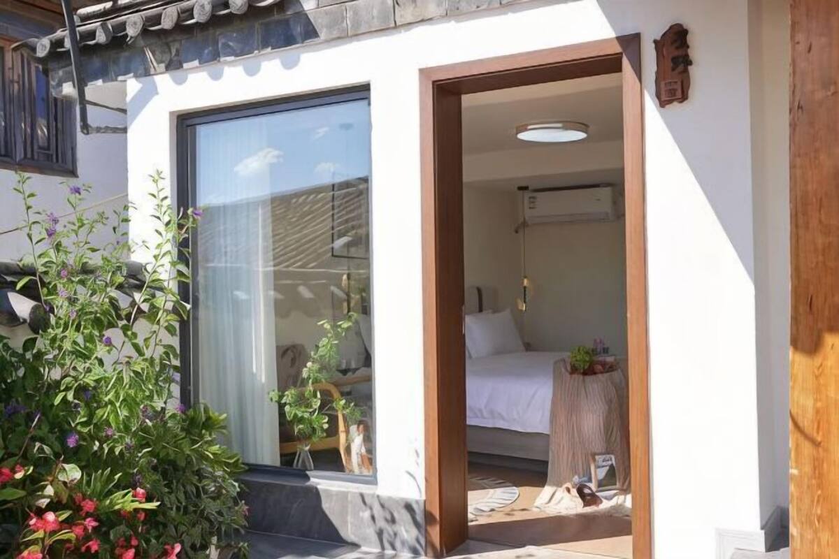 Une chambre d’hôtel avec une porte coulissante, un lit, une table de chevet et une petite plante en pot.