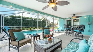 Eine sonnendurchflutete Terrasse mit Pool, Gartenmöbeln und Deckenventilatoren.