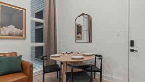 Un comedor con una mesa redonda de madera, sillas negras y un espejo en la pared.