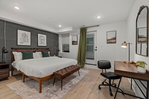 A modern bedroom with a wooden bed, a desk, and a chair. There are framed pictures on the wall and a large mirror. - SLEEP 8 In 2 New Townhouses in the BEST walking location in Old Philadelphia! (Philadelphia)