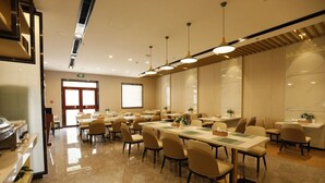 Un'ampia sala conferenze con vari tavoli e sedie, un angolo cottura e un'ampia finestra che garantisce luce naturale.