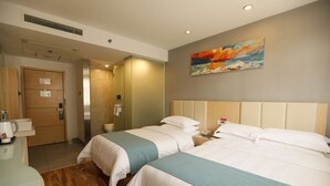 Una camera d'albergo con due letti, un quadro appeso al muro, una macchina per caffè e l'ingresso del bagno.
