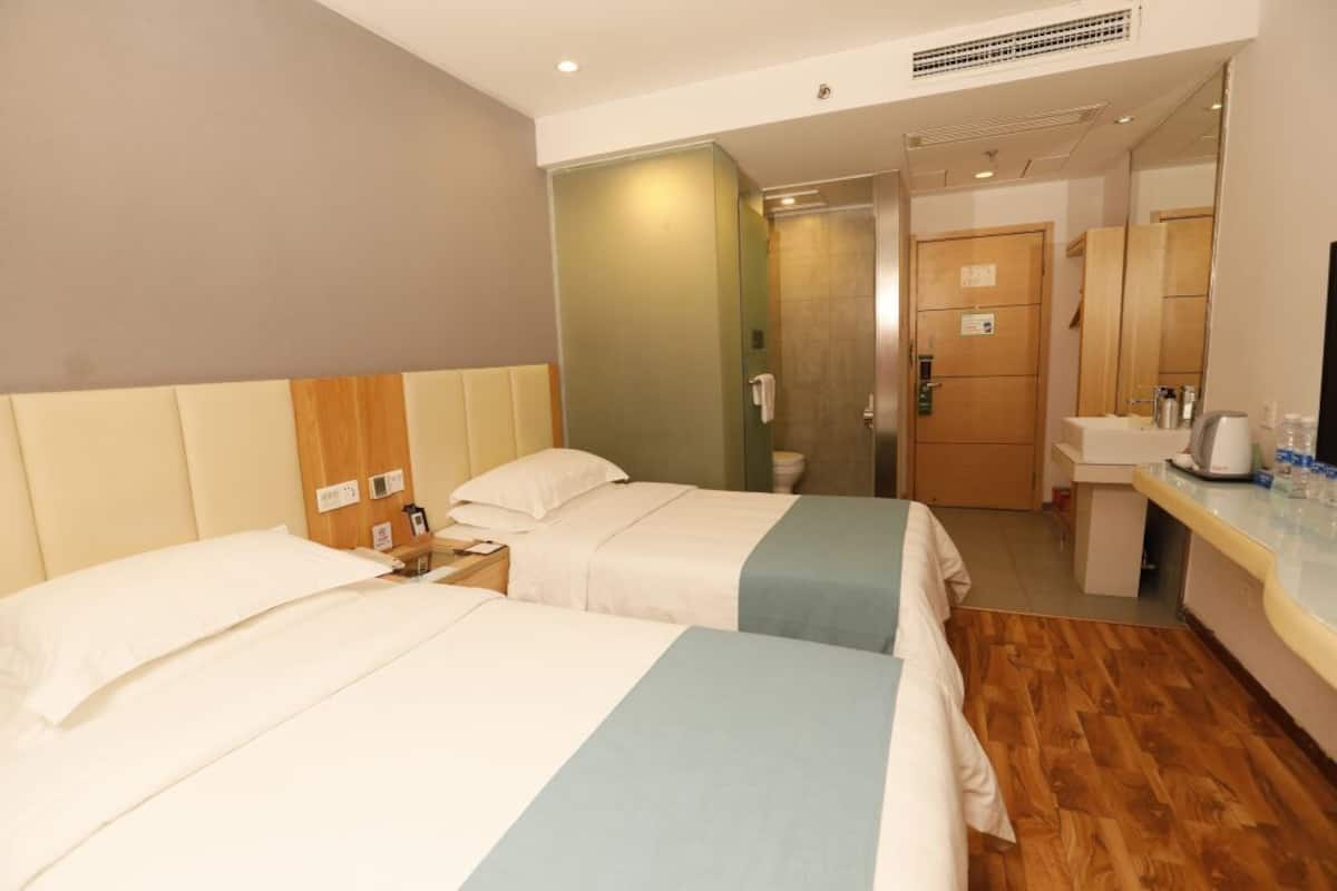 A hotel room with two beds, a bathroom, and a kitchenette.