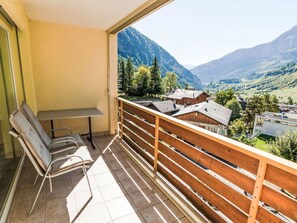 Enjoy breathtaking views of the surrounding mountains from this balcony, featuring a table and two chairs.