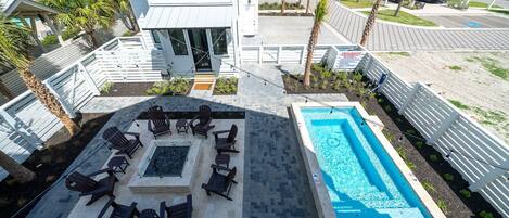 A rooftop pool area with lounge chairs and a fire pit.