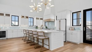 Et moderne køkken med hvide skabe, en stor ø med barstole og et backsplash i fiskebensmønster.