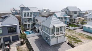 A coastal residential area with multiple two-story houses featuring gabled roofs and balconies. - Deja View - Ocean Views for Miles with Private Pool, Hot Tub, Game Room & Easy Beach Access (Port Aransas)