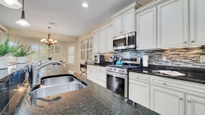 A modern kitchen with granite countertops, stainless steel appliances, and white cabinetry.