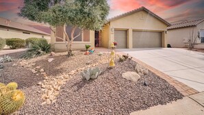 A residential house with a garage, a driveway, and a garden with cacti and a tree.