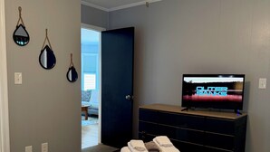 A hotel room with a bed, a ceiling fan, a television, and a door leading to a balcony. - Poseidon’s Mini Getaway: Serene Outer Banks Retreat Near the Beach (Kitty Hawk)