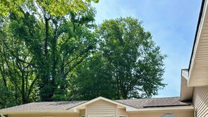 A two-story house with a covered porch and a pathway leading to the garage. - Poseidon’s Mini Getaway: Serene Outer Banks Retreat Near the Beach (Kitty Hawk)