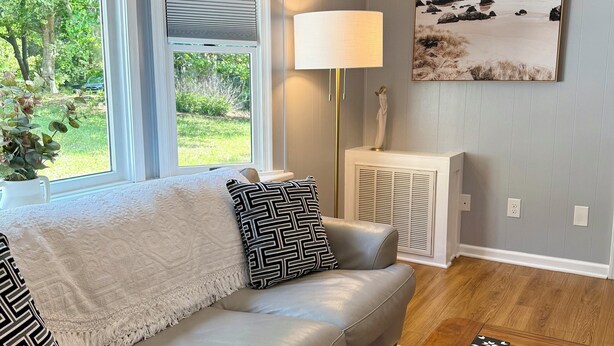 A living room with a beige sofa, a wooden coffee table, and a painting on the wall. - Poseidon’s Mini Getaway: Serene Outer Banks Retreat Near the Beach (Kitty Hawk)