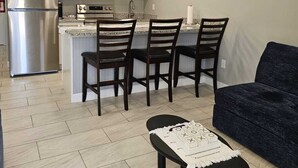 Une cuisine moderne avec des meubles blancs, un réfrigérateur en acier inoxydable et un îlot central doté de tabourets de bar.