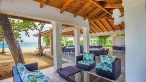 An outdoor seating area with wicker furniture and a view of the beach. - Rheia Properties - Sosua Ocean Village (Sosúa)