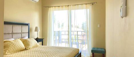 A bedroom with a bed, a nightstand, a ceiling fan, and a window with curtains.