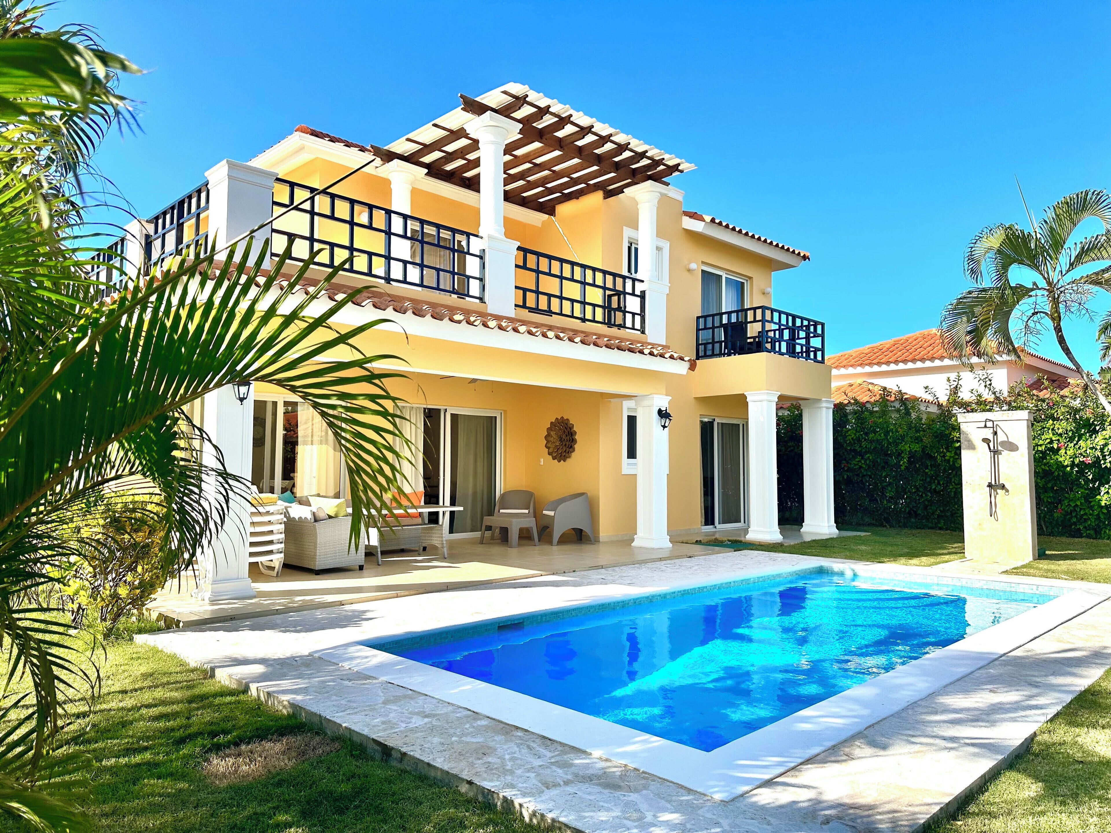 A two-story house with a swimming pool, a balcony, and a well-maintained garden.