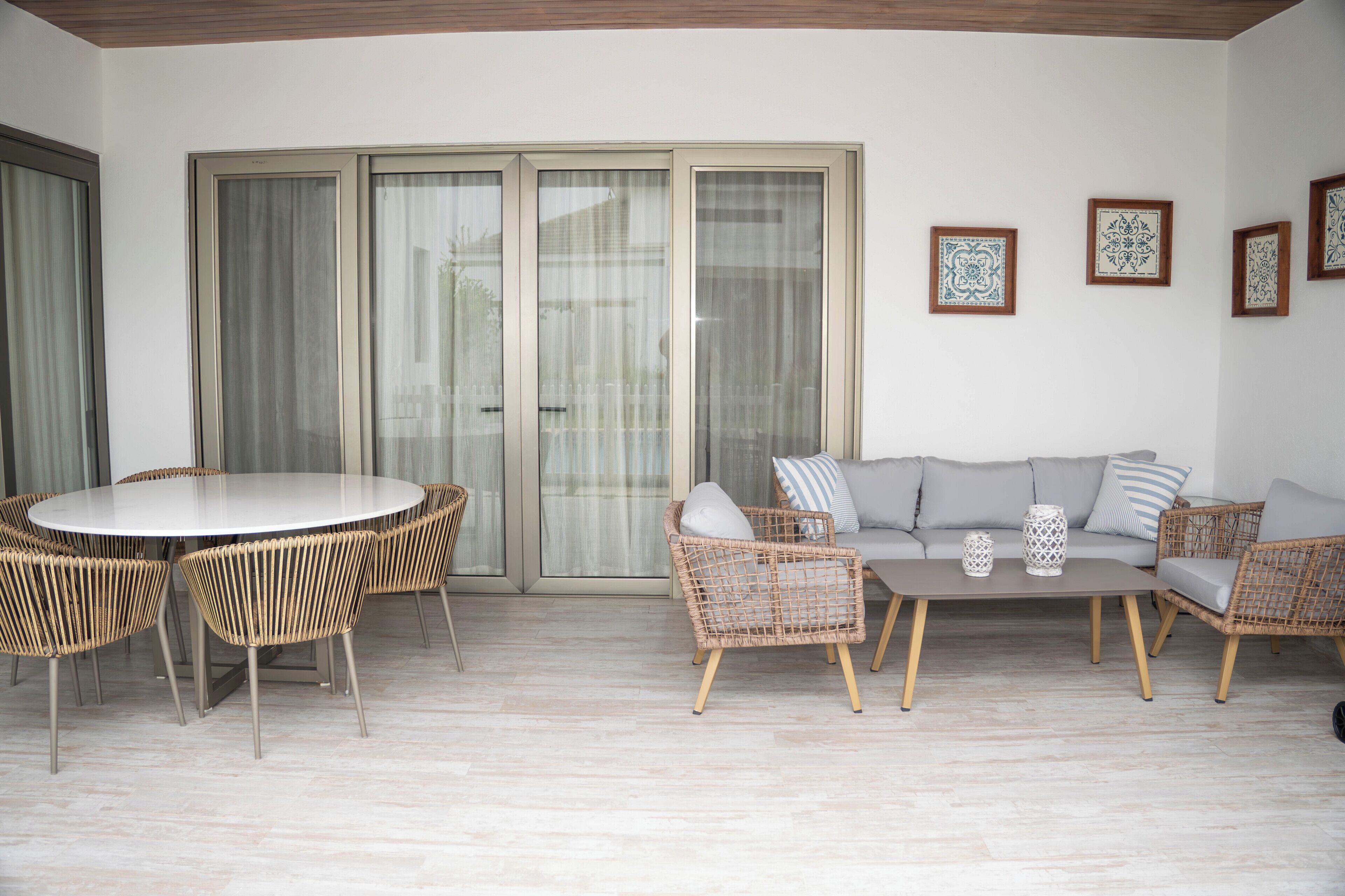Una habitación con una mesa de comedor redonda, sillas de mimbre, un sofá gris y una mesa auxiliar.