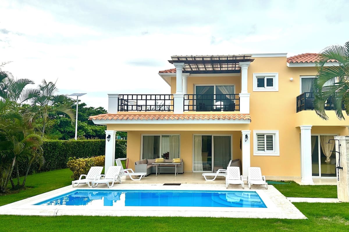 A two-story house with a balcony, a swimming pool, and a well-maintained garden.