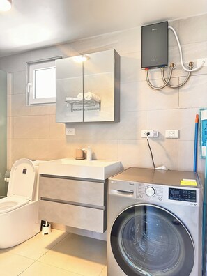 A modern bathroom with a toilet, sink, and washing machine.