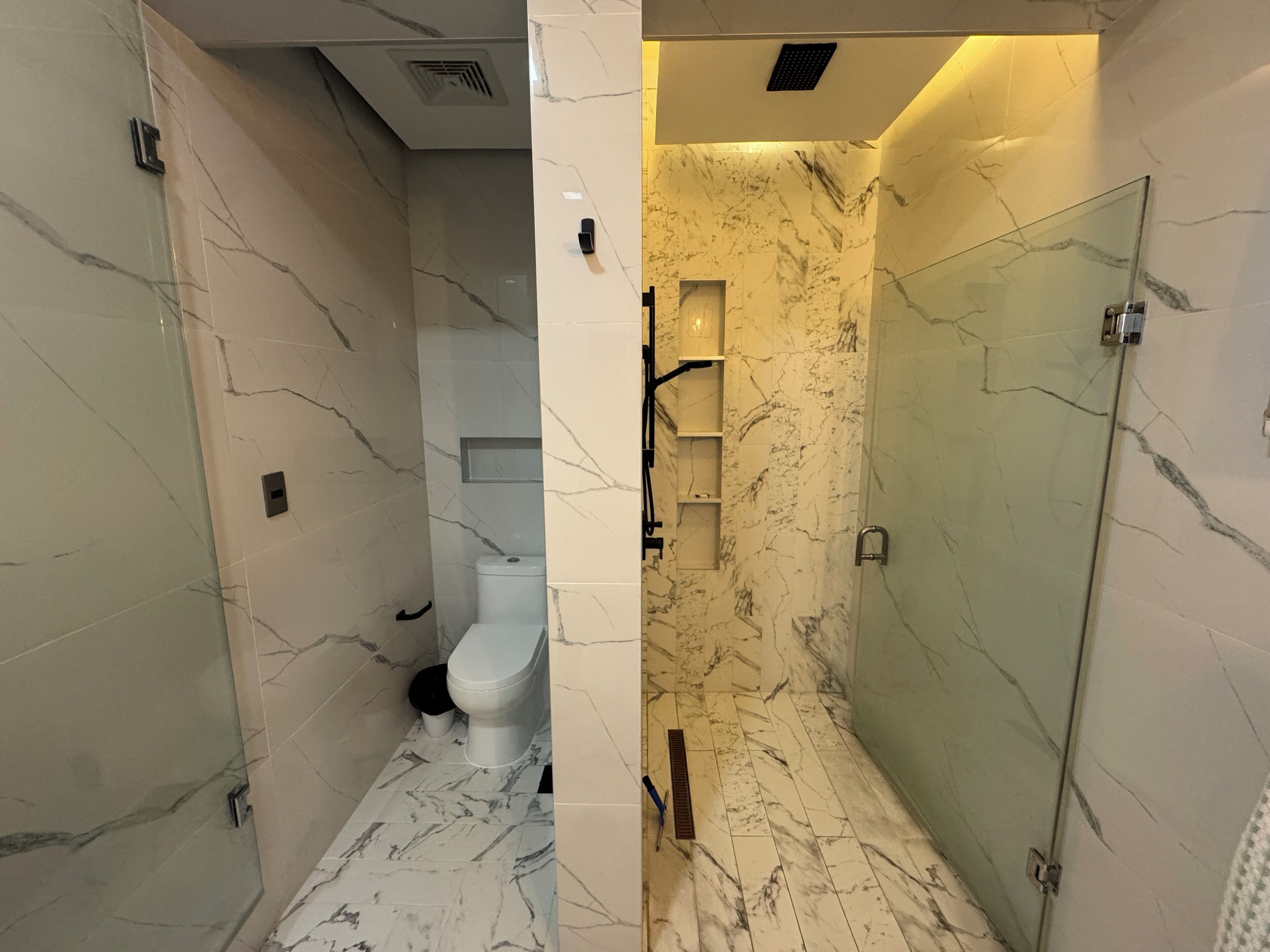 Ein Badezimmer mit Toilette, Dusche und Glastür.