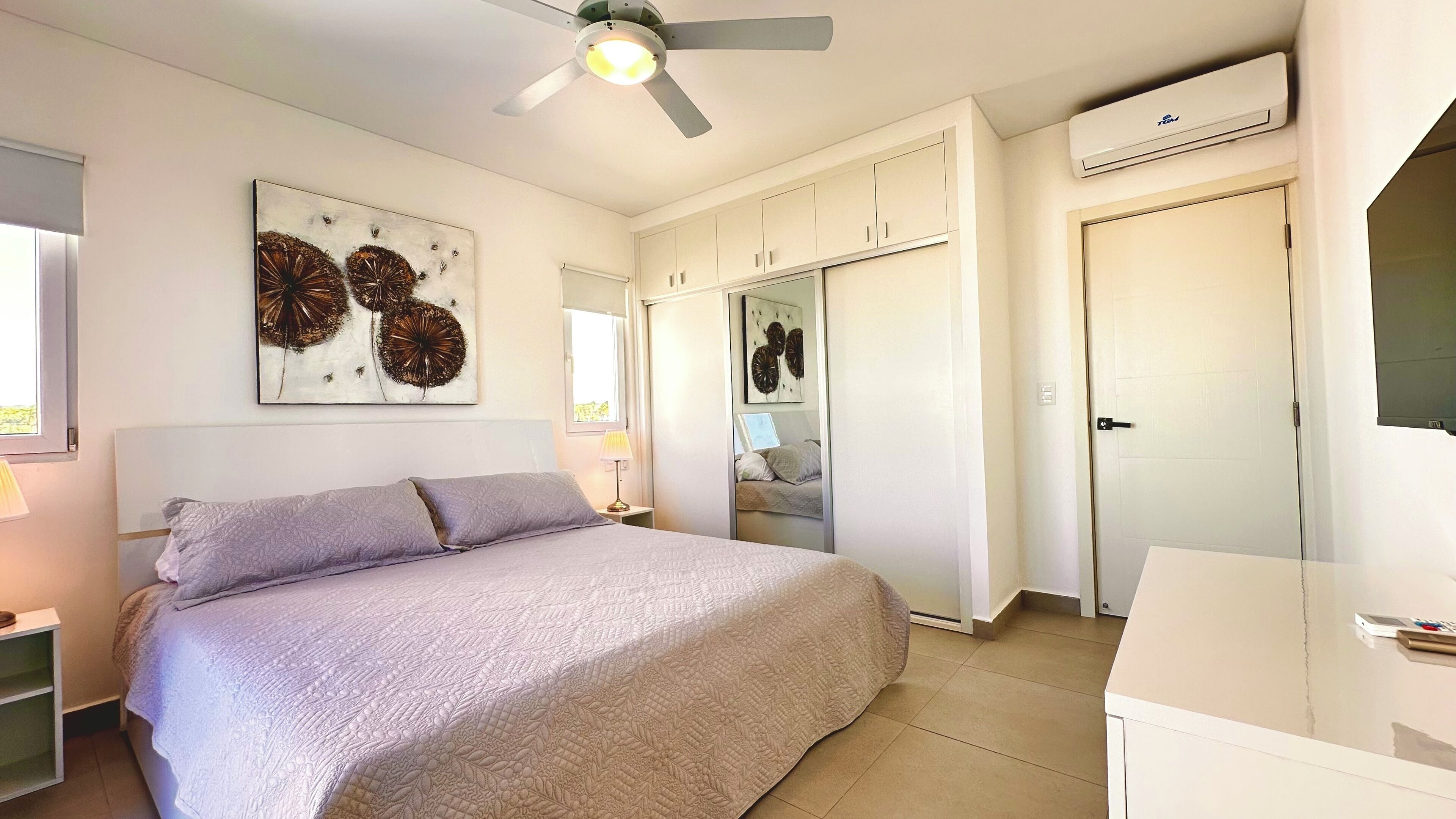 Quarto com cama, ventoinha no teto, ar condicionado e armário.