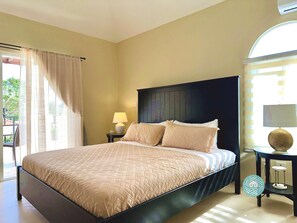 A bedroom with a bed, a nightstand, a lamp, and a window with curtains.