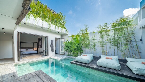 A modern outdoor pool area with a wooden deck, lounge chairs, and a glass-enclosed bedroom. - Luxury 4-Bedroom Holiday Rental Near Berawa Beach, Bali Villa 2094 (Bali)