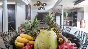 A fruit bowl with bananas, pineapples, and dragon fruit on a table in a modern interior space with a ceiling light fixture. - Luxury 4-Bedroom Holiday Rental Near Berawa Beach, Bali Villa 2094 (Bali)