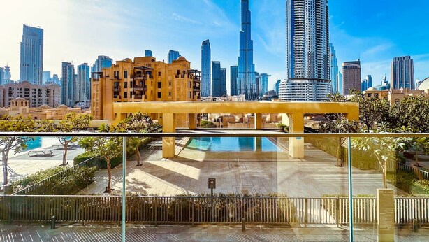 A modern hotel with a rooftop pool, a view of the city skyline, and a prominent building in the background. - Spectacular Burj View 2BR Luxury (Dubai)
