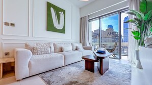 A modern living room with a sofa, coffee table, and a large window offering a city view. - Spectacular Burj View 2BR Luxury (Dubai)