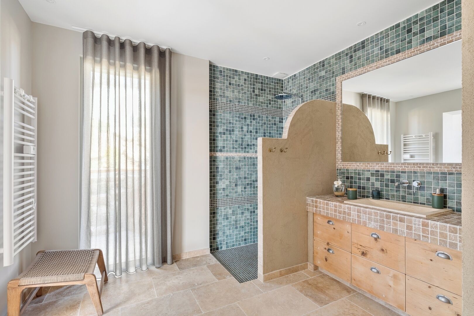 A modern bathroom with a shower, a vanity with a mirror, and a window with curtains.