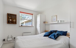 Une chambre à coucher comprenant un lit, une fenêtre, une armoire et une étagère ornée d’objets décoratifs.