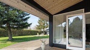 A modern house with a wooden deck, a large sliding glass door, and a potted plant.