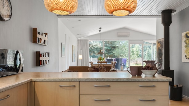 A modern kitchen with wooden cabinets, a central island, and pendant lighting.
