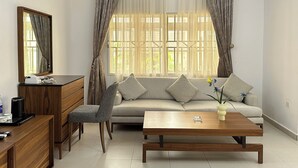A modern living room with a sofa, a coffee table, a TV stand, and a chair. - JUN YUE Abuja hotel (Abuja)