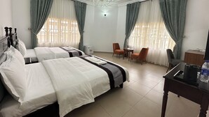 A hotel room with two beds, a chandelier, a table with a kettle, and two chairs. - JUN YUE Abuja hotel (Abuja)