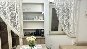 Un coin repas avec une table dressée pour quatre personnes, entourée de chaises, et un vase avec des fleurs posé sur la table.