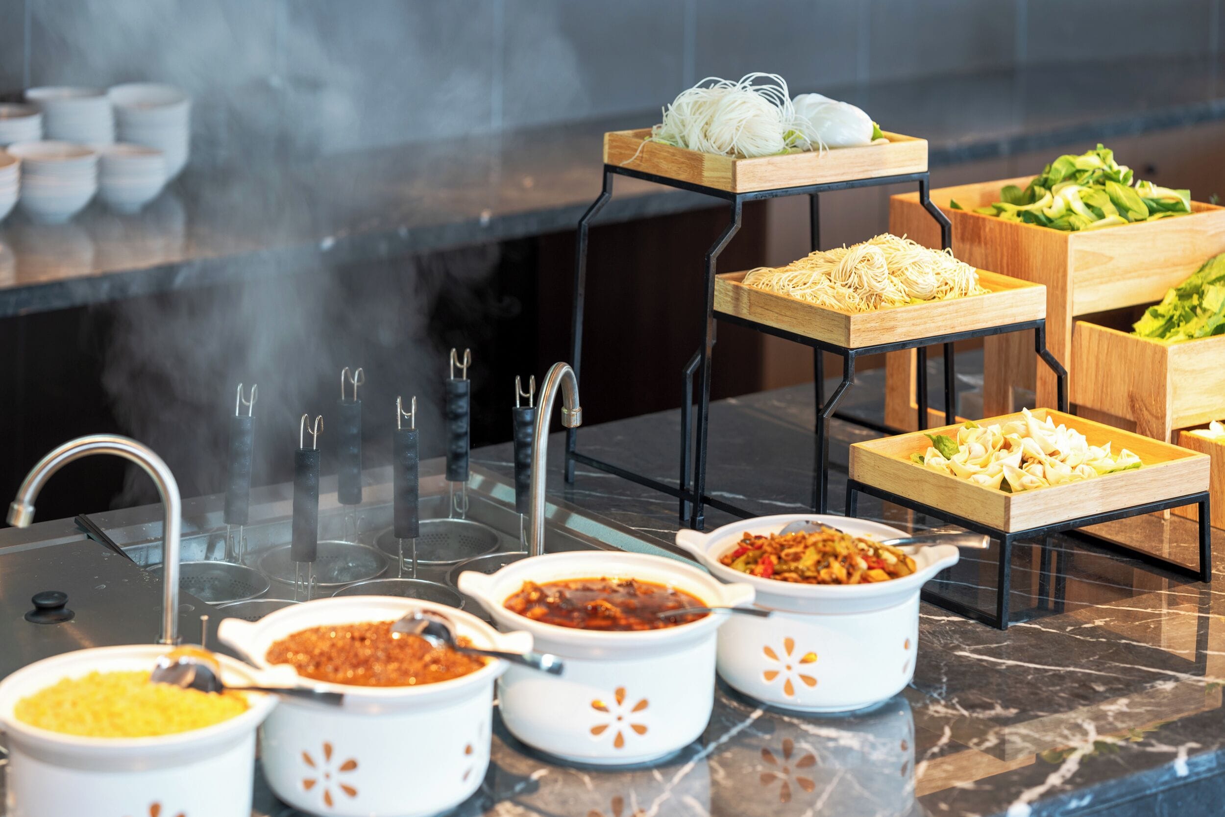 A buffet setup with various dishes and a steam vent.