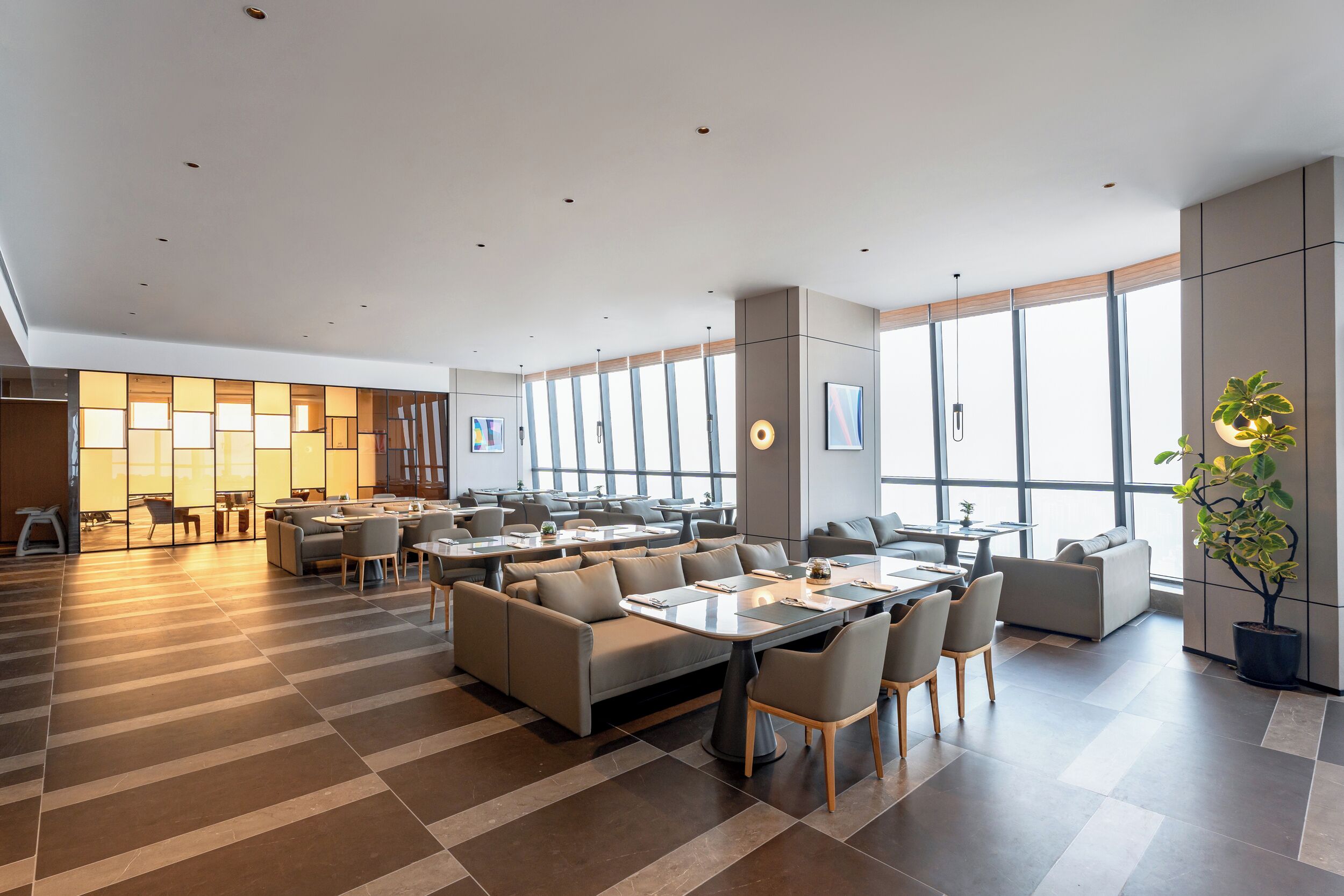 Un hall d’hôtel spacieux, doté de nombreux espaces de détente, de grandes fenêtres et d’un design moderne.