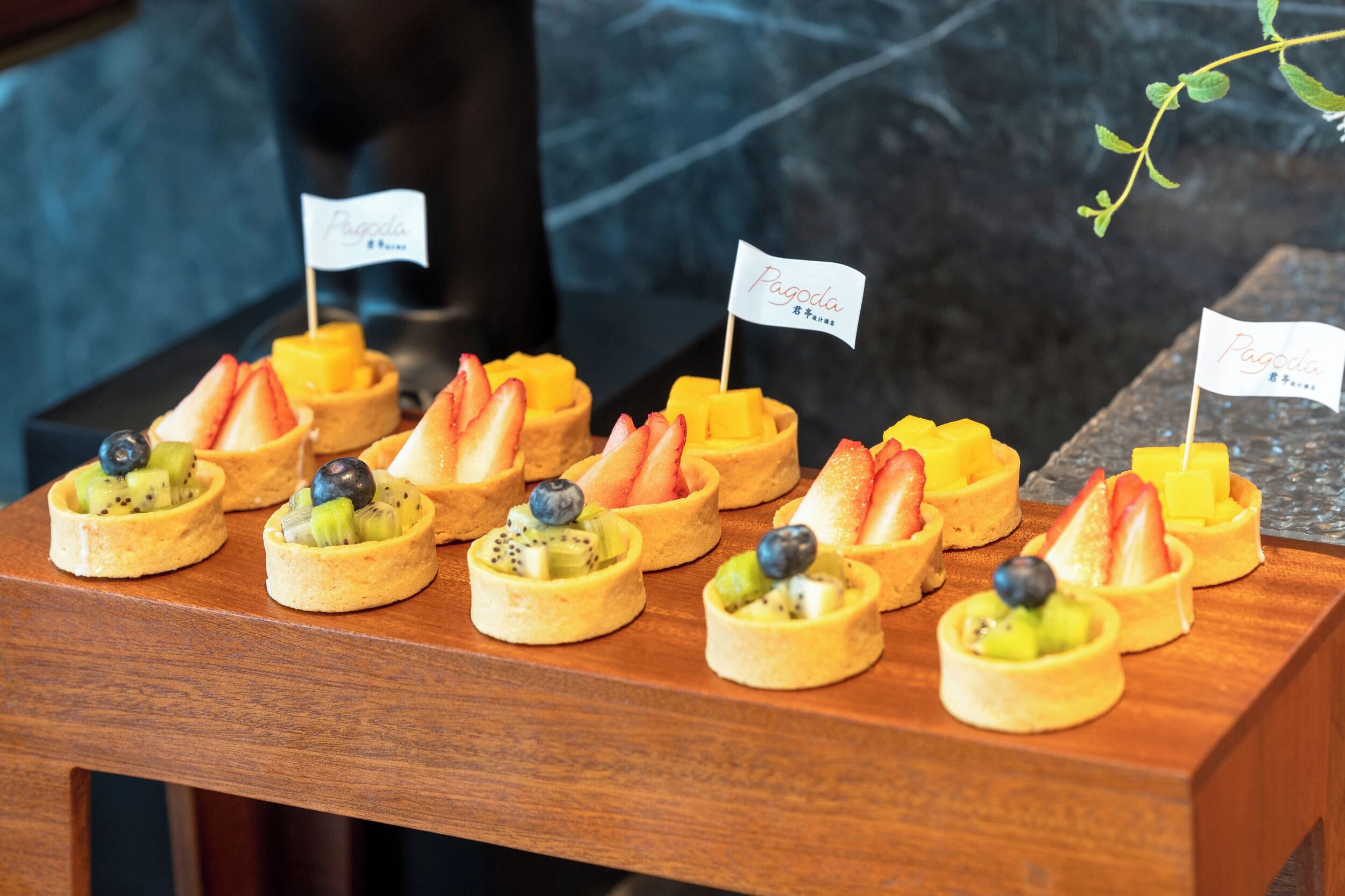 A wooden table with fruit tarts labeled "Pagoda."