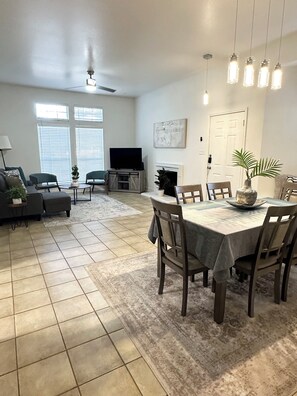 A spacious living room with a fireplace, a dining area with a table and chairs, and a television in the background. - Prime NW Austin TX near Domain, Apple, Oracle, high tech corridor upgraded home! (Austin)