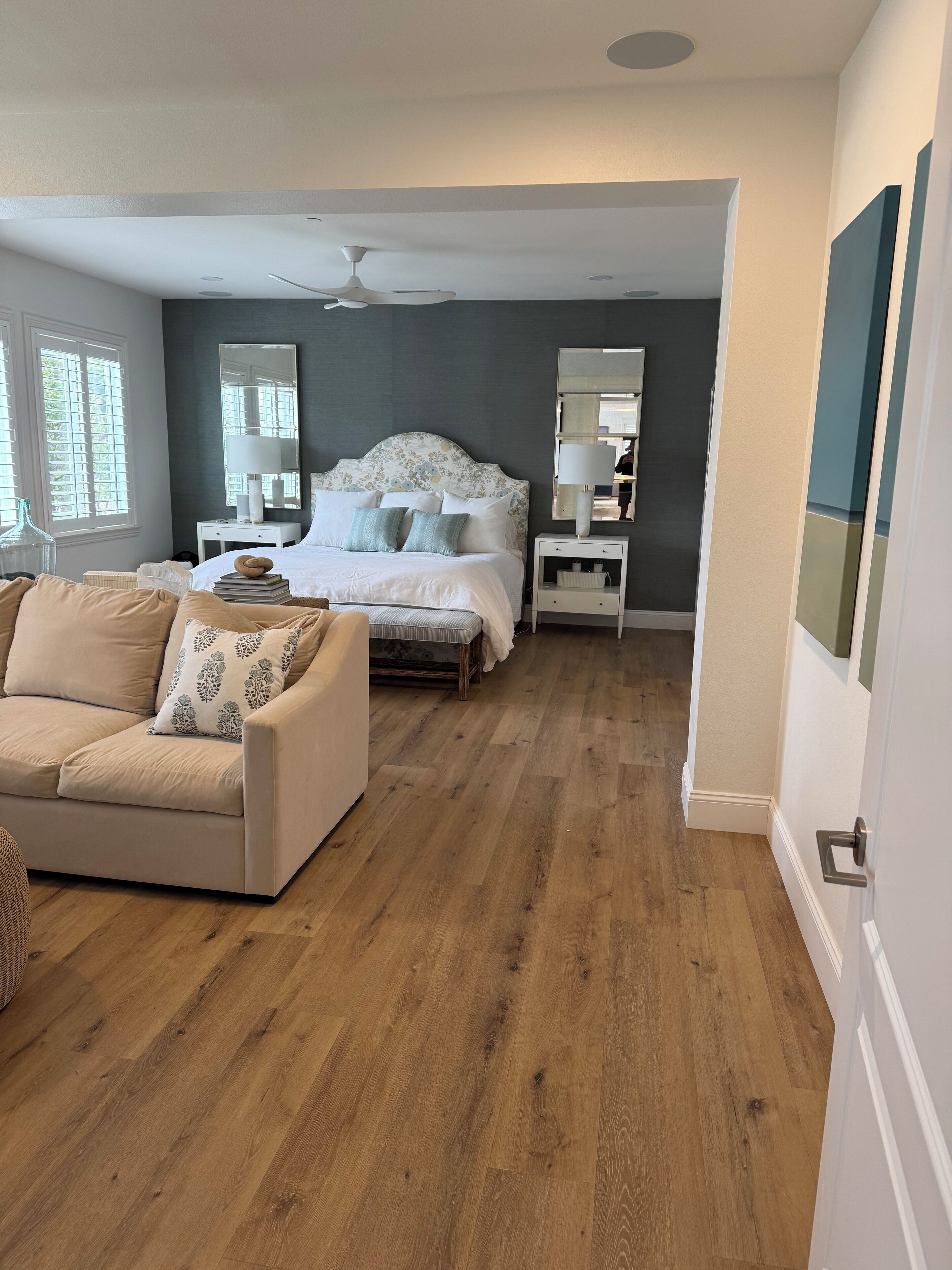 A bedroom with a bed, bedside tables, a nightstand, a sofa, and a large mirror.