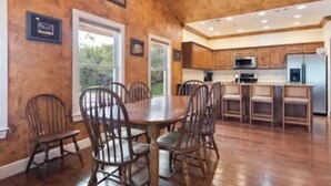 A spacious dining area with a wooden table and chairs, adjacent to a kitchen with wooden cabinets and modern appliances.