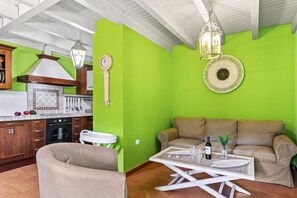 A living room with a sofa, a coffee table, and a kitchen in the background. - La Ensertal - country house with pool in Ribadesella, Northern Spain (Alea)