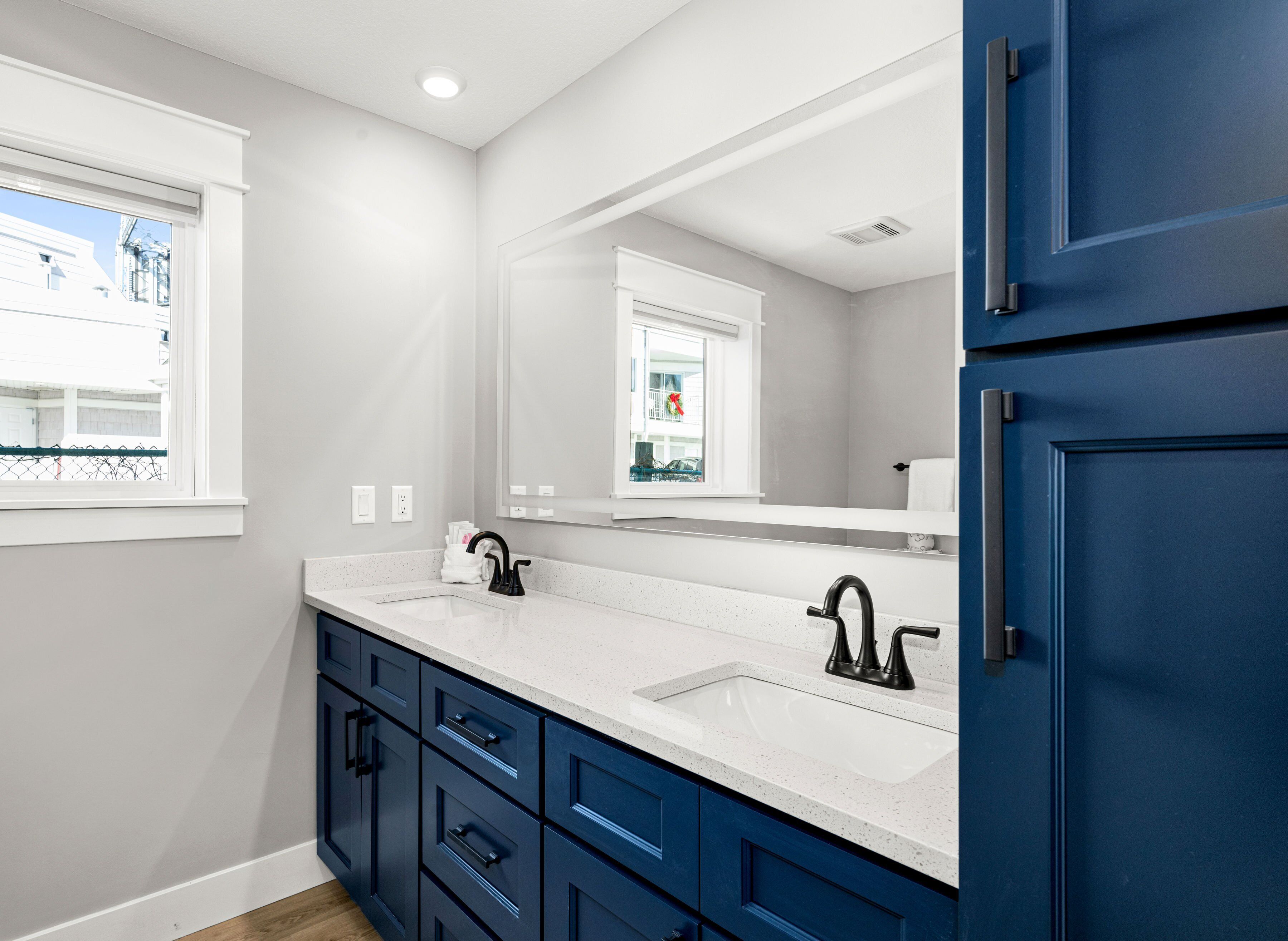 A modern bathroom with a white countertop, two sinks, and a large mirror.