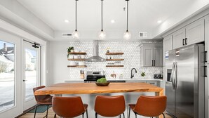 A modern kitchen with a central island, stainless steel appliances, and pendant lighting. - Luxury Condo w/ Beach Access | Dragestil 717-1 (Duluth)